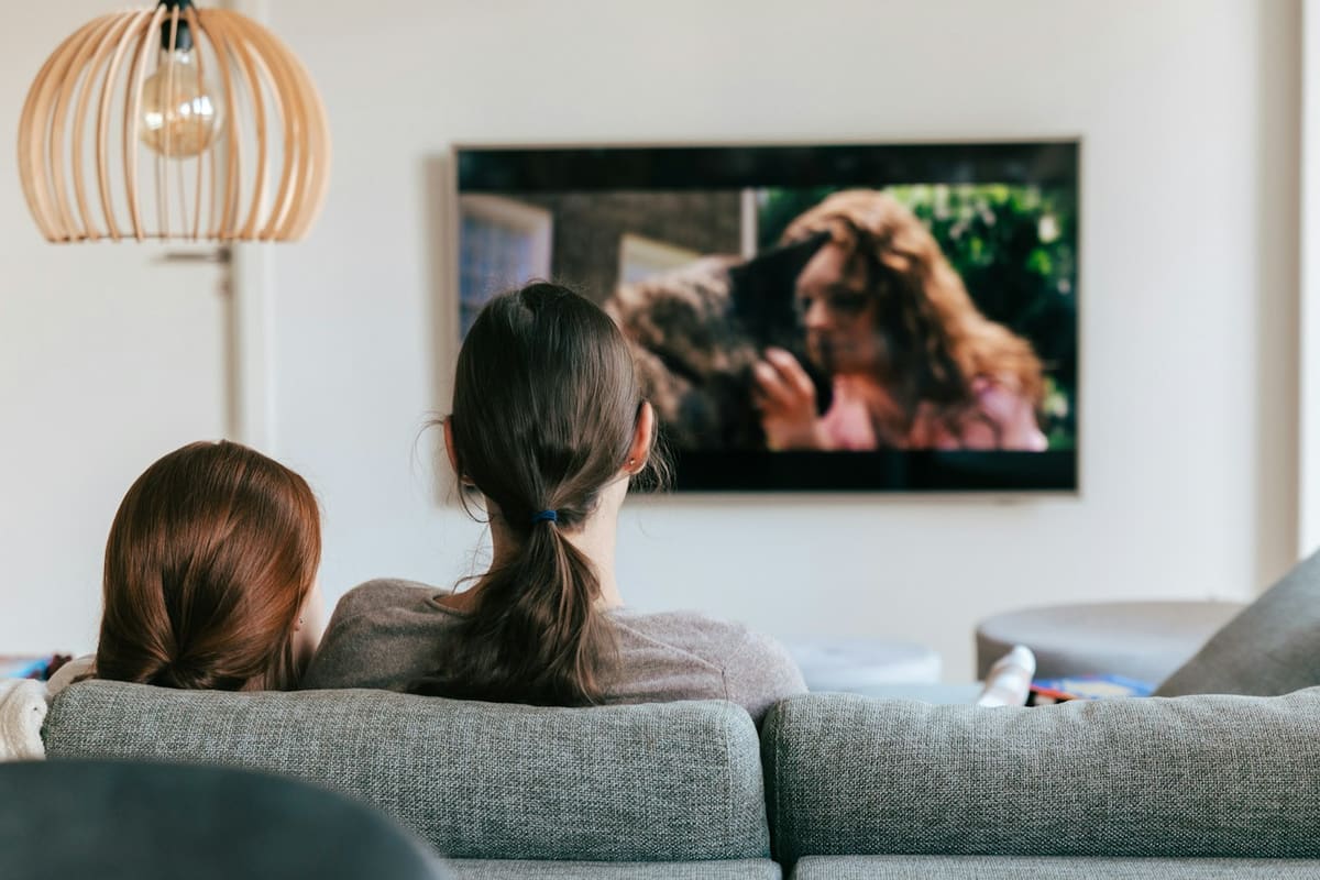 Zwei Personen sitzen auf dem Sofa und schauen fern